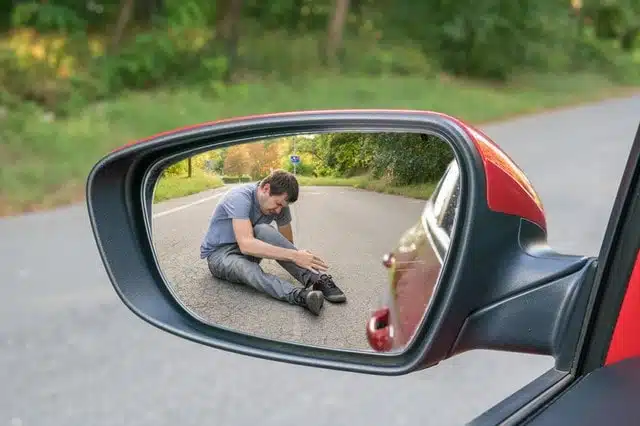 Hit and run concept. View on injured man on road in rear mirror of a car. min Hit and run concept. View on injured man on road in rear mirror of a car. min